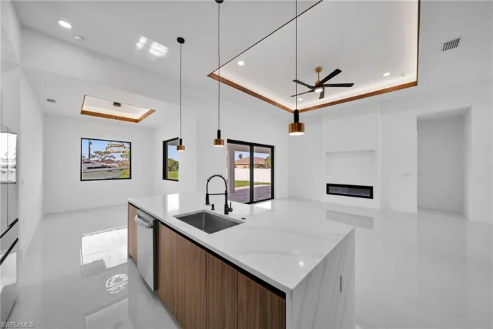 Kitchen with sink, ceiling fan, a raised ceiling, and light tile patterned floors