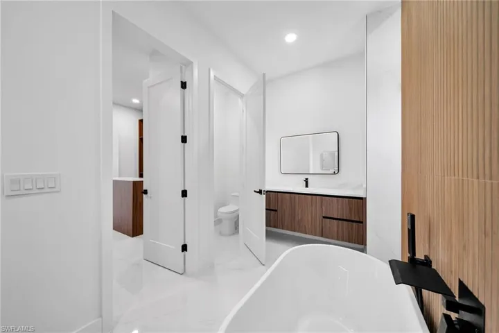 Bathroom featuring tile patterned floors, toilet, vanity, and a bath