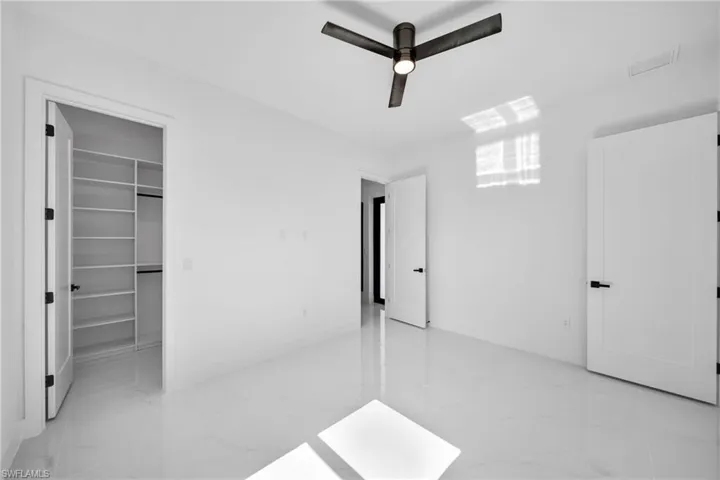 Unfurnished bedroom with a closet, light tile patterned flooring, a spacious closet, and ceiling fan