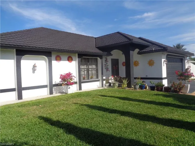 Ranch-style house with an attached garage, a front lawn, stucco siding, and metal roof