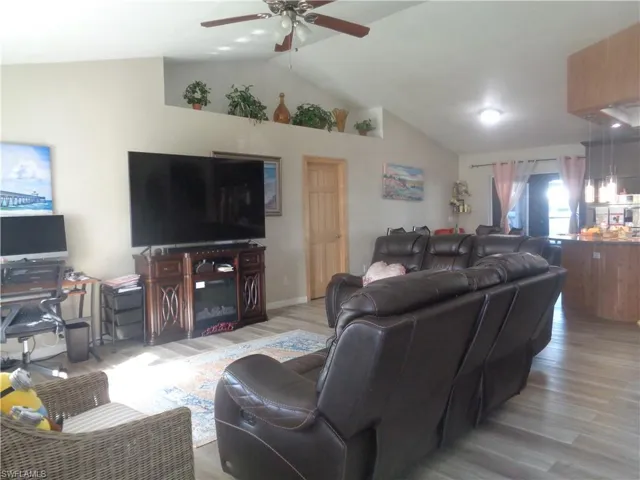 Living area featuring lvaulted ceiling, light wood-style flooring, and a ceiling fan