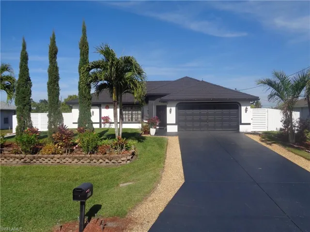 Front view of single story home featuring driveway, an attached garage, stucco siding, and metal roof