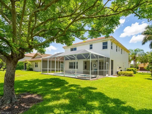 Back of house with a lawn and a lanai