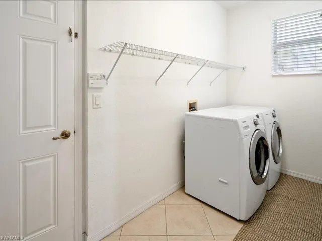 Laundry area featuring washer and clothes dryer, washer hookup, and light tile floors