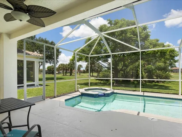View of swimming pool with a lanai, an in ground hot tub, a yard, ceiling fan, and a patio
