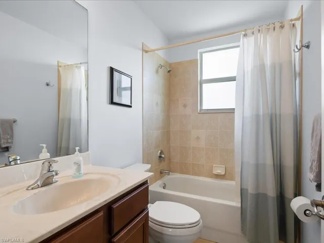 Full bathroom featuring shower / bathtub combination with curtain, toilet, and vanity