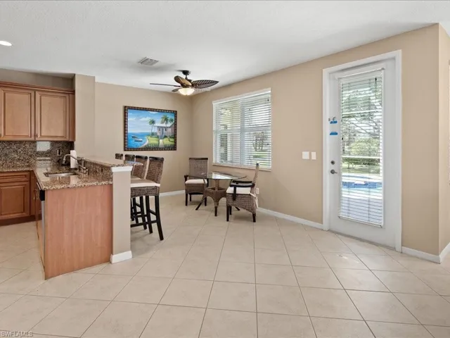 Kitchen featuring a kitchen breakfast bar, ceiling fan, tasteful backsplash, light stone counters, and sink