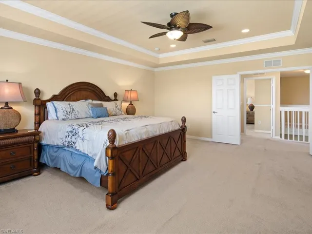 Bedroom featuring carpet, ceiling fan, a raised ceiling, and crown molding