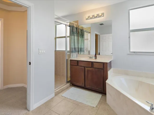 Bathroom with tile floors, vanity, and shower with separate bathtub