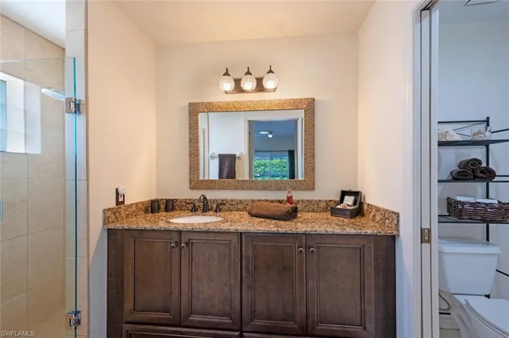 Primary walk in shower on left, vanity in center, private commode area on right.