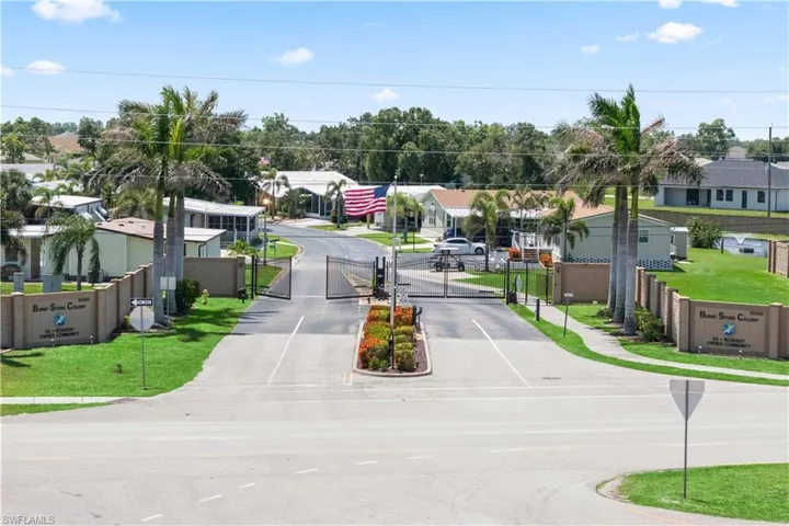 This aerial shot captures the attractive entryway with decorative plants, a controlled access gate, and nearby sidewalks that enhance curb appeal and safety.