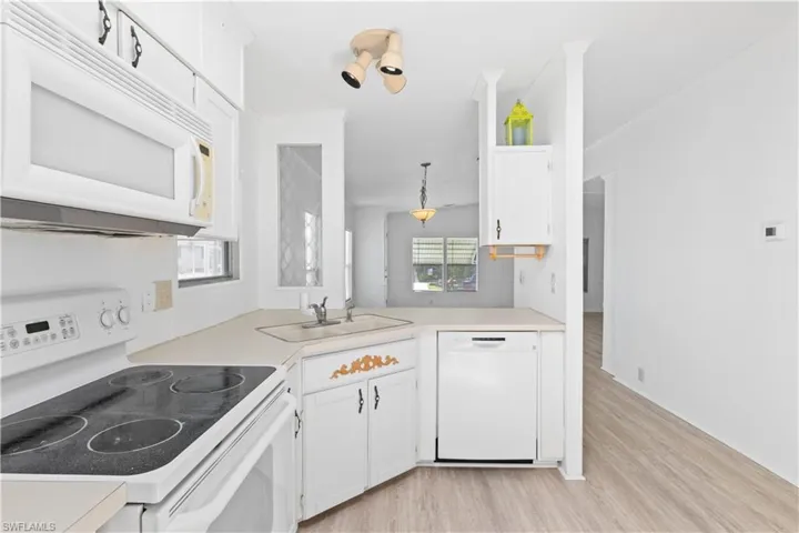 The kitchen combines practicality and style with white appliances, ample counter space, and bright windows that let in plenty of sunlight.