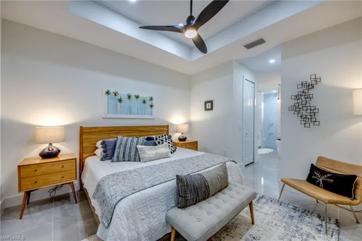 Tiled bedroom featuring a closet, ensuite bathroom, and ceiling fan