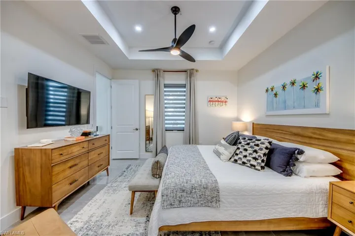 Bedroom with tile floors, ceiling fan, and a tray ceiling