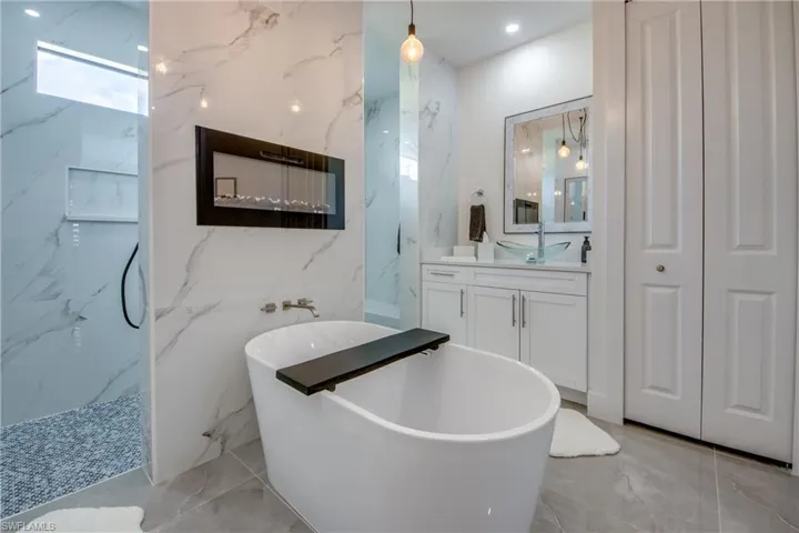 Bathroom with tile flooring, vanity, and tile walls