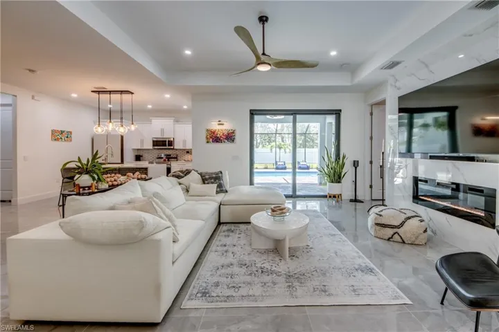 Living room with ceiling fan, a raised ceiling, and sink