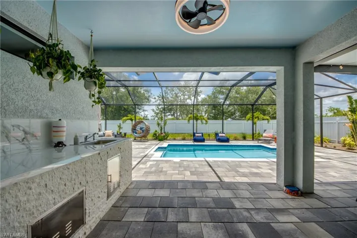 View of swimming pool with sink, an outdoor kitchen, a lanai, and a patio