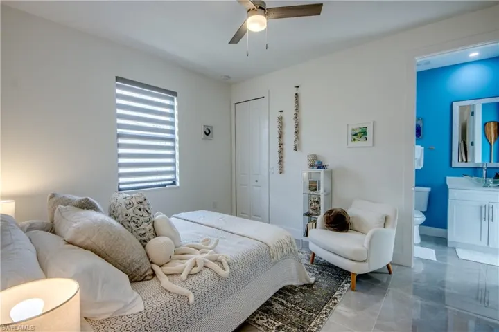 Tiled bedroom featuring ceiling fan, a closet, and ensuite bathroom