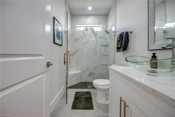 Bathroom featuring walk in shower, vanity, toilet, and tile floors