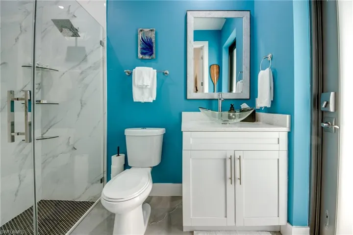 Bathroom with tile floors, a shower with door, vanity with extensive cabinet space, and toilet