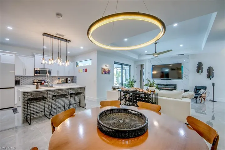 Tiled dining area with ceiling fan, a tray ceiling, and sink