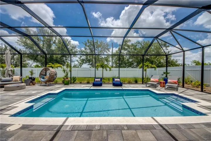 View of swimming pool featuring glass enclosure and a patio area
