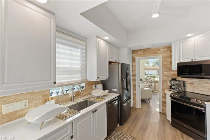 Kitchen with white cabinetry, farmhouse sink, stainless steel appliances, and white quartz countertops