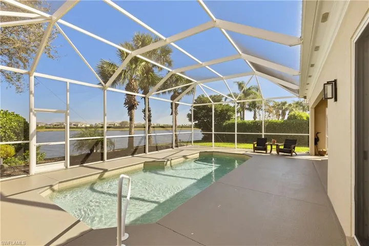 View of pool with screened enclosure with no-seeum screens, a patio area, and a water view