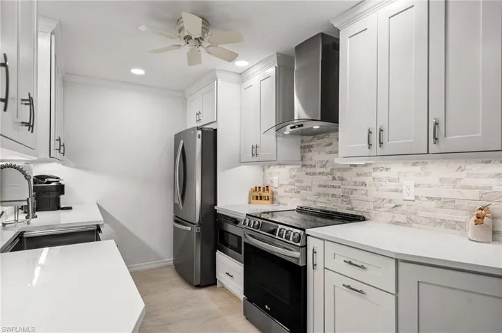 Kitchen featuring white cabinetry, appliances with stainless steel finishes, and wall chimney exhaust hood