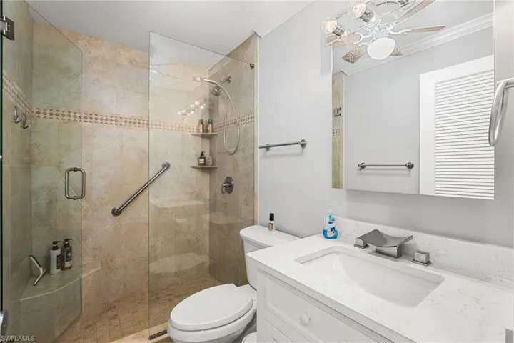 Bathroom with a shower with shower door, vanity, toilet, and ornamental molding