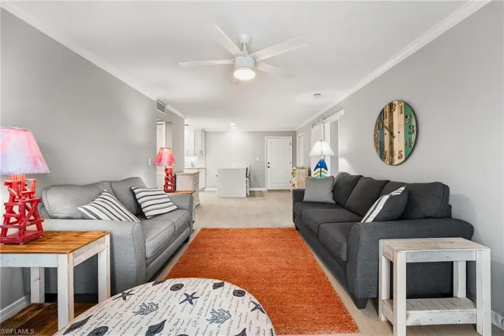 Living room with ceiling fan, crown molding, and light hardwood / wood-style flooring