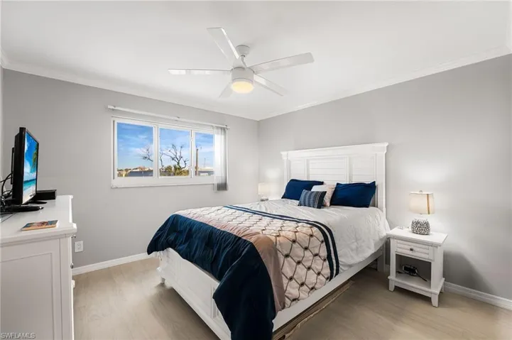 Bedroom featuring light wood-type flooring, ceiling fan, and ornamental molding