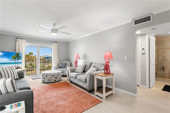 Living room with light wood-type flooring, ceiling fan, and ornamental molding