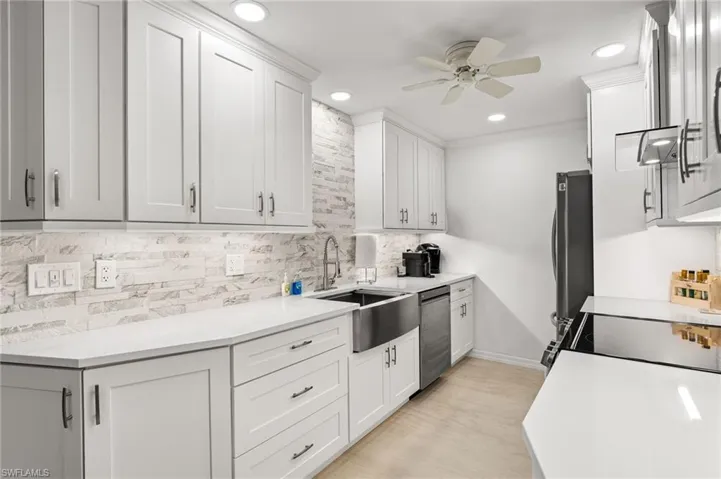 Kitchen with ceiling fan, backsplash, sink, appliances with stainless steel finishes, and white cabinets