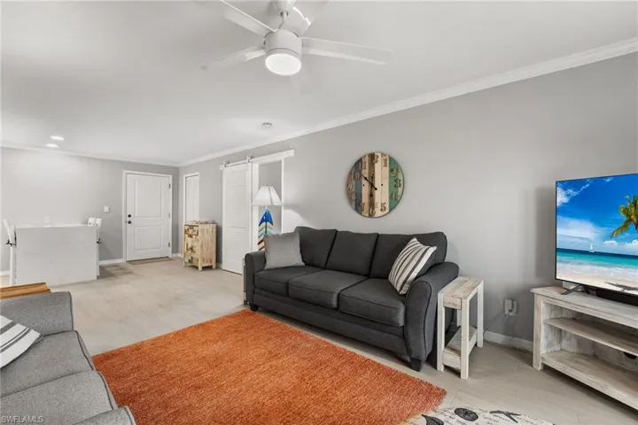Living room featuring ceiling fan, ornamental molding, and light hardwood / wood-style floors