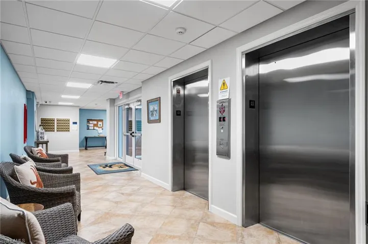 Corridor with elevator, french doors, and a paneled ceiling