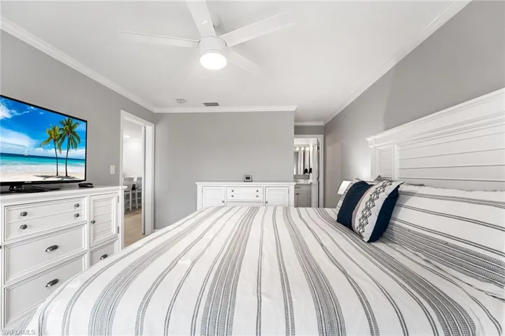 Bedroom featuring ceiling fan, ensuite bathroom, and ornamental molding