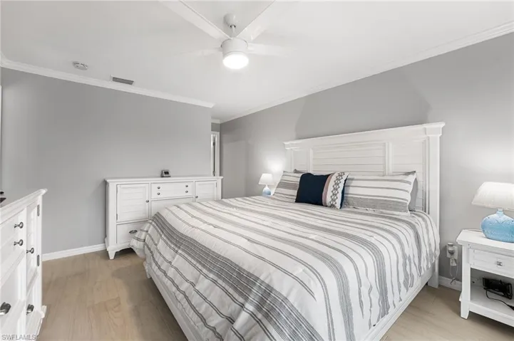 Bedroom featuring ceiling fan, light wood-type flooring, and ornamental molding