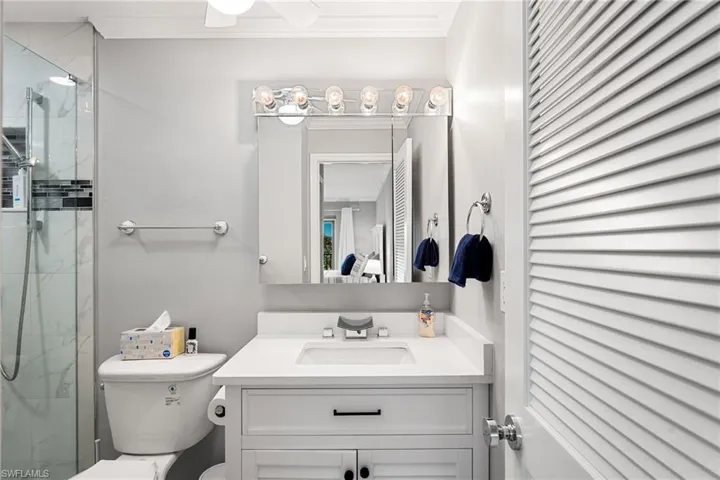 Bathroom featuring vanity, toilet, ornamental molding, and an enclosed shower