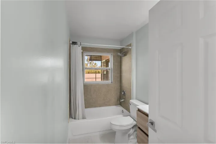 Full bathroom featuring toilet, shower / bathtub combination with curtain, and vanity