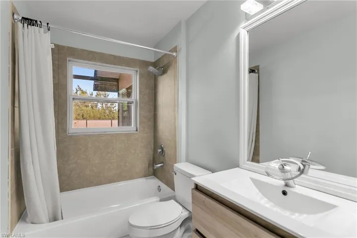 Full bathroom with toilet, vanity, and shower / bath combo