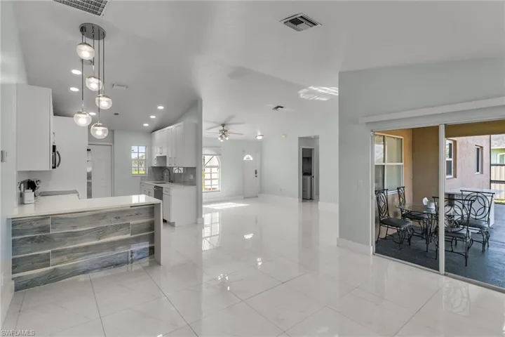 Kitchen featuring vaulted ceiling, decorative light fixtures, white cabinetry, ceiling fan, and sink