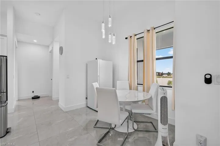 Bright interior space featuring a window with exterior views, light tile flooring, and a modern pendant light fixture