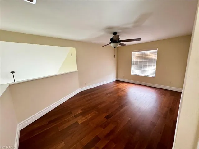 Empty room with ceiling fan, dark wood finished floors, and baseboards