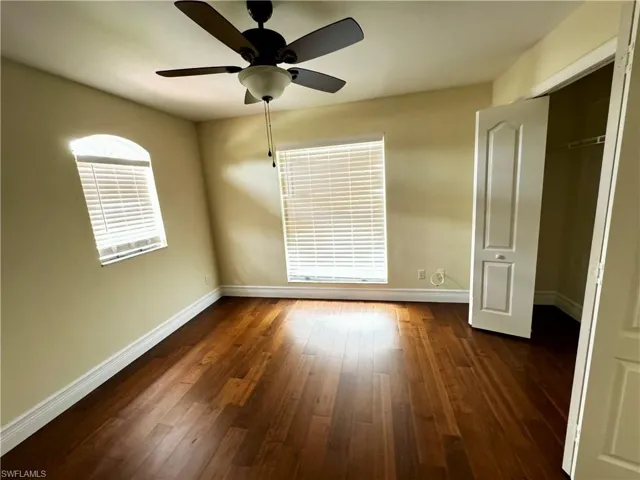 Unfurnished bedroom with baseboards, dark wood finished floors, a closet, and ceiling fan