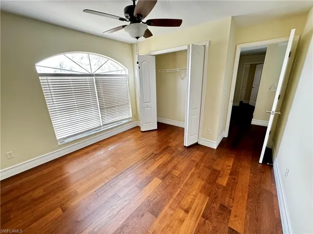Unfurnished bedroom with wood finished floors, a closet, baseboards, and ceiling fan