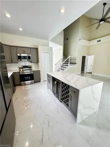 Kitchen featuring stainless steel appliances, light marble finish flooring, recessed lighting, gray cabinets, and a ceiling fan