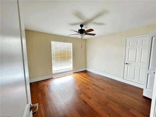 Spare room with a ceiling fan, wood finished floors, and baseboards