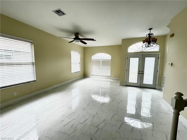 Foyer entrance featuring marble finish flooring, a chandelier, french doors, and baseboards