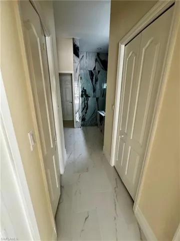 Hallway with light marble finish floors and baseboards